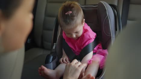 a baby girl is safely secured in a car seat.