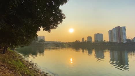 golden orange yellow sunset above lake in urban area, static view