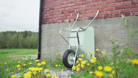 Wheel-Barrow-Leaning-On-A-House-With-Brick-Wall-At-The-Backyard