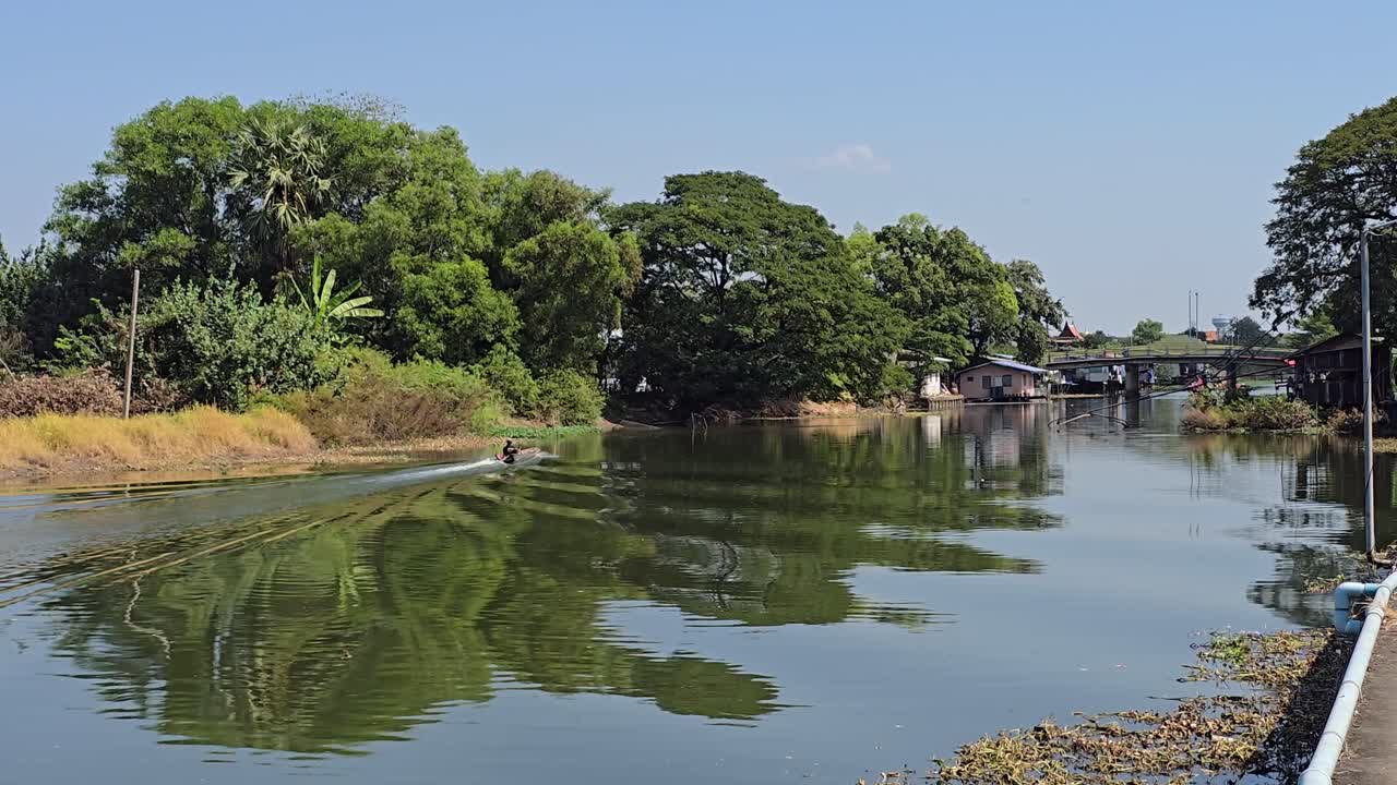 Barca a coda lunga che risale il canale Khlong in Thailandia in una giornata di sole.