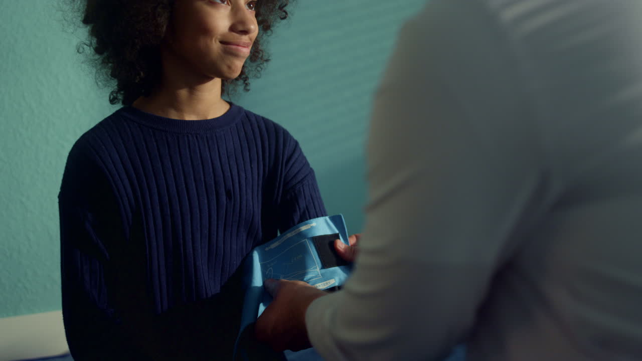 pediatra poniendo el brazalete del tonometro en el brazo de un niño adolescente en primer plano.