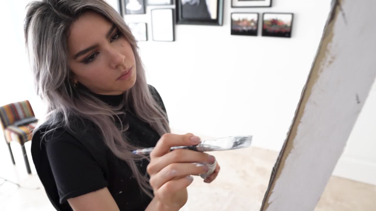 artista pintando con alta concentración, joven mujer latina en primer plano