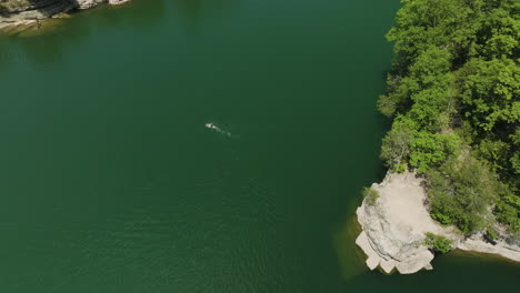 Drone-Splashdown,-a-bird's-eye-view-of-a-person-swimming-in-Beaver-Lake,-Hogscald-Hollow,-Arkansas,-USA
