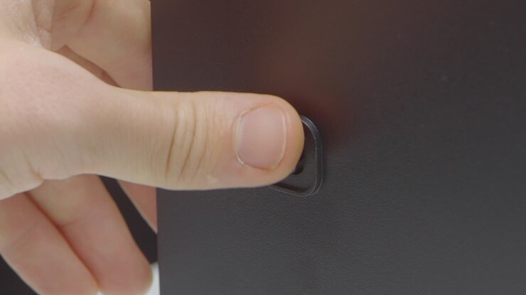 Hand pushing a button on a dark cabinet door