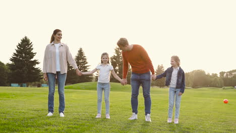 Glückliche-Familie,-Die-Hände-Hält-Und-Zusammen-Im-Park-Springt