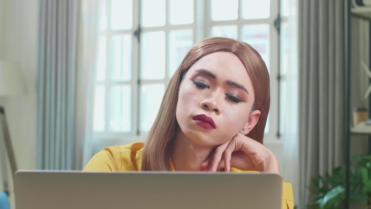Bored Asian Young Transgender Woman Working With Laptop Computer In Living Room
