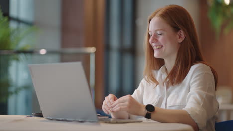 Una-Mujer-Pelirroja-Feliz-Está-Chateando-En-Línea-Por-Web-Hablando-Con-La-Cámara-De-Una-Computadora-Portátil-Y-Sonriendo-Tecnología-De-Comunicación-Remota