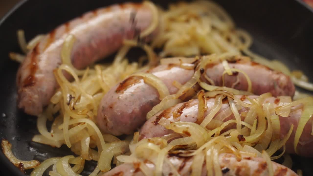 cocinero anónimo agregando salsa de soja en la sartén con cebolla y salchichas