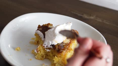 female hand while eating sweet banana cake topped with whip cream