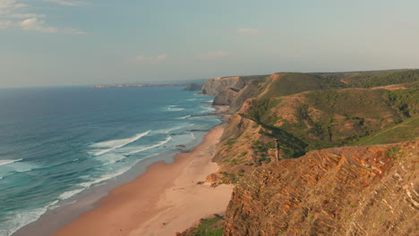 aerial: a man standing on a viewpoint watching the surfers in portugal