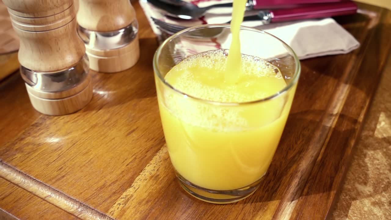 jugo de naranja en un vaso, el desayuno de la mañana, cámara lenta con seguimiento de rotación.