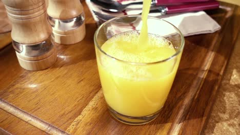 Jugo-De-Naranja-Vertido-En-Un-Vaso,-El-Desayuno-De-La-Mañana.-Cámara-Lenta-Con-Seguimiento-De-Rotación.