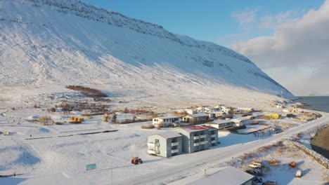 Aerial-view-of-Isafjordur-town,-Iceland,-drone-flying-above-houses,-snowy-background-mountain,-forward