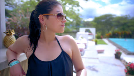 Portrait-shot-of-young-woman-in-sunglasses-and-bathing-suit-by-pool