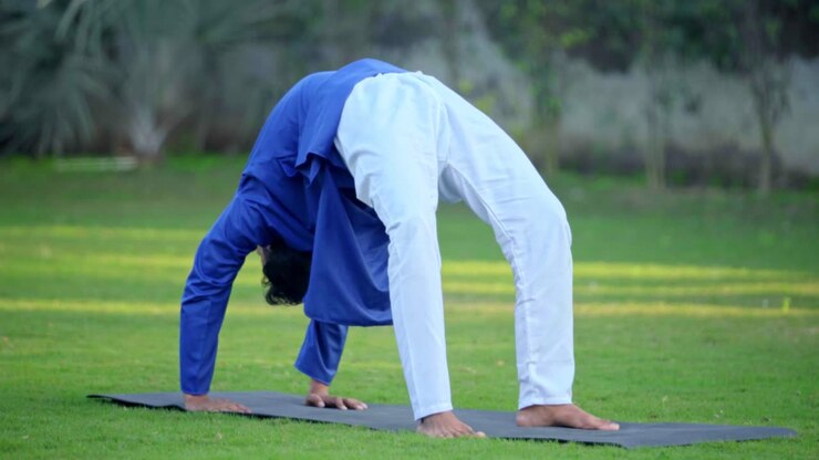 hombre indio haciendo pose de yoga de rueda