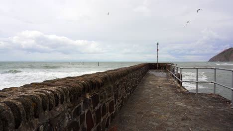 waves crash around the harbor wall and sea defences of lynmouth on a windy day