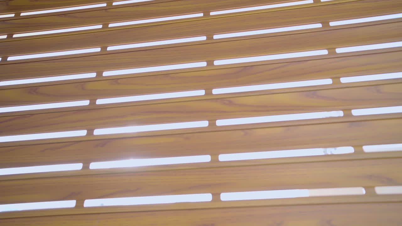 Rays of light shine through blinds and illuminate a dark room in close-up