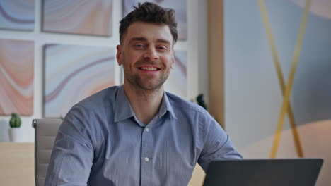 calm man enjoying break sitting office desk closeup. businessman looking camera