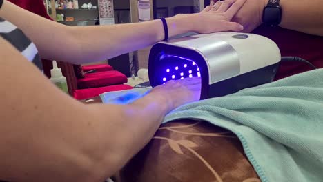 young woman receiving a gelish nail manicure in bangkok, thailand