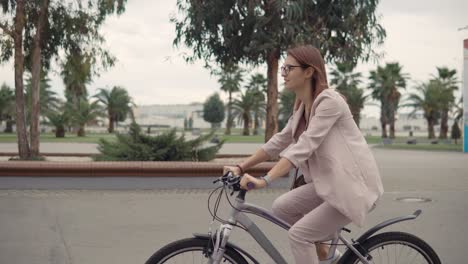 woman in pink business suit cycling in city park