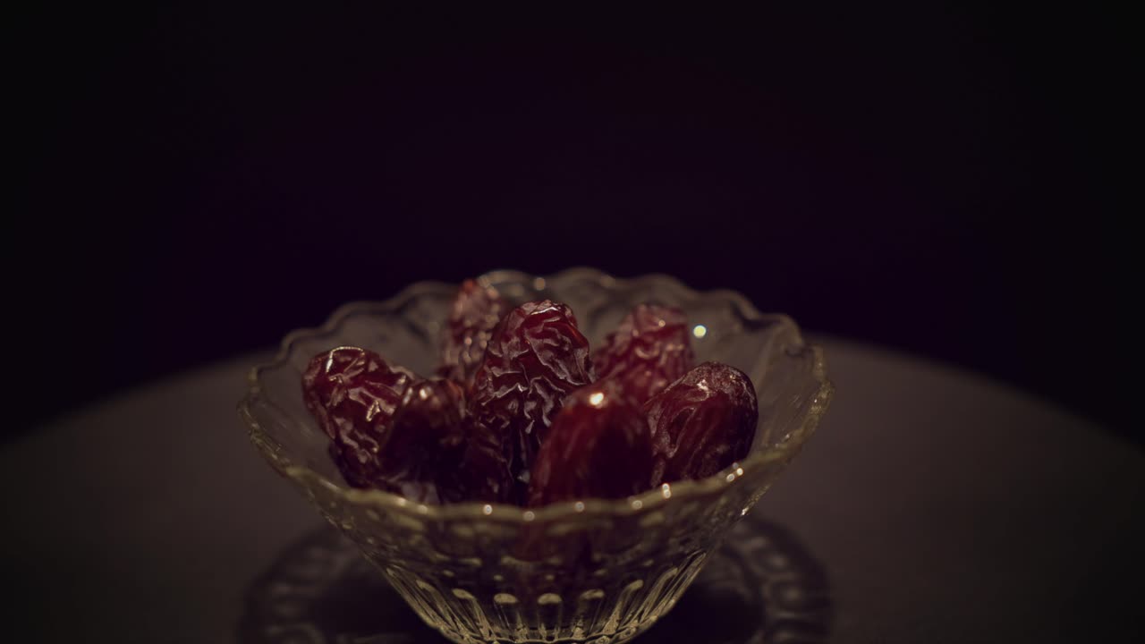 high quality texture Medjool dates in spinning glass bowl under spotlight