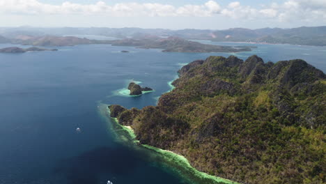 Tropical-island-surrounded-by-beach-and-boats-at-Palawan-Philippines---High-angle-aerial-with-coastal-background