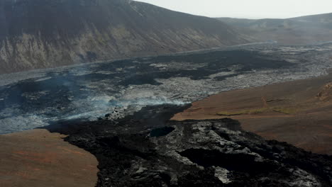 Fly-above-cooling-lava-stream,-contouring-terrain.-Volcanic-landscape-after-volcano-eruption.-Fagradalsfjall-volcano.-Iceland,-2021