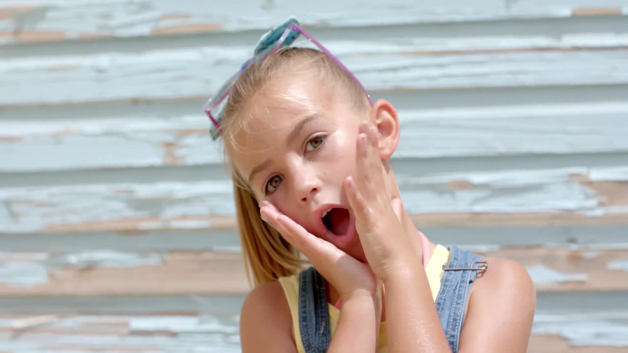 Ritratto di ragazza caucasica felice che si tocca il viso davanti a una casa sulla spiaggia