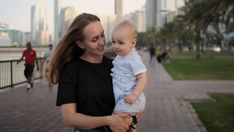 Young-mother-with-a-child-and-first-steps.-Young-mother-with-a-child-at-outdoor-learninig-for-a-first-steps-near-urban-in-the-city