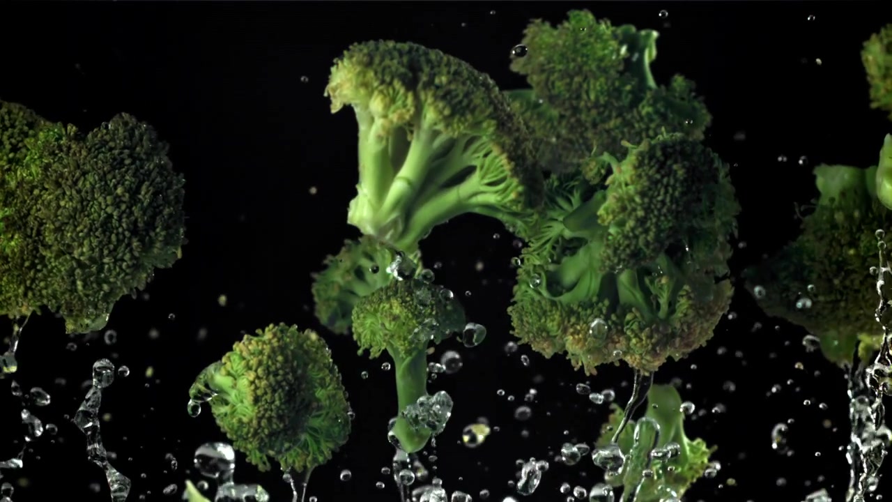 Cimette di broccoli freschi e verdi che schizzano nell'acqua al rallentatore