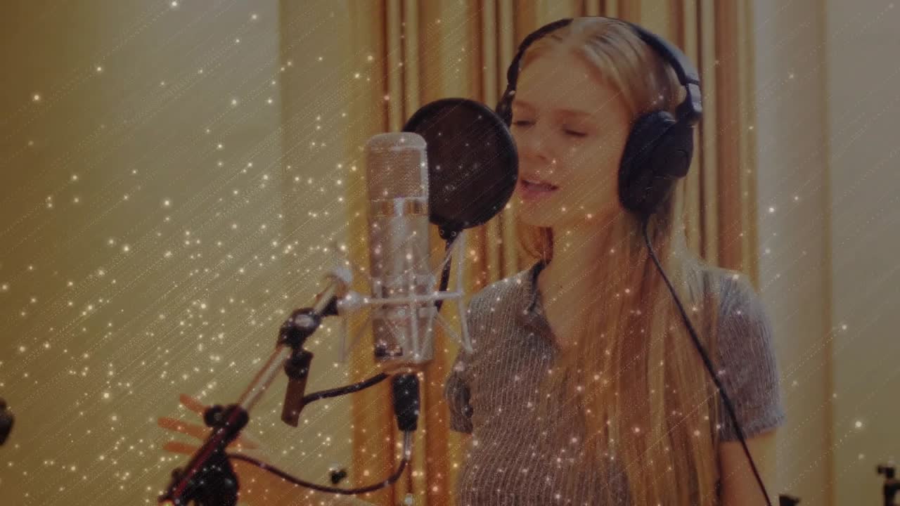 Sångerska med hörlurar sjunger i popmikrofon och spårar sång i studio, med ett glittrande överlägg runt sångerskan.