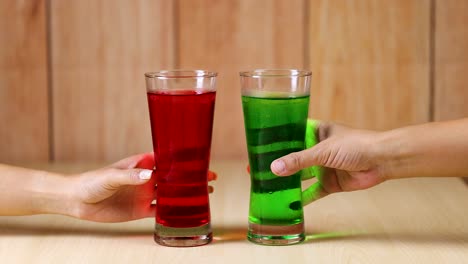 dos manos sonando bebidas rojas y verdes