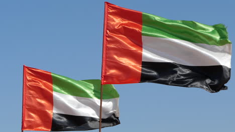 united arab emirates uae national flags, blue sky background slomo