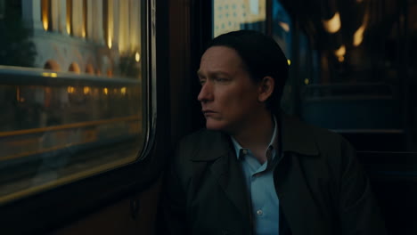 man looking out train window at night