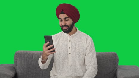 Fröhlicher-Sikh-Indianer,-Der-über-Einen-Videoanruf-Mit-Grünem-Bildschirm-Spricht