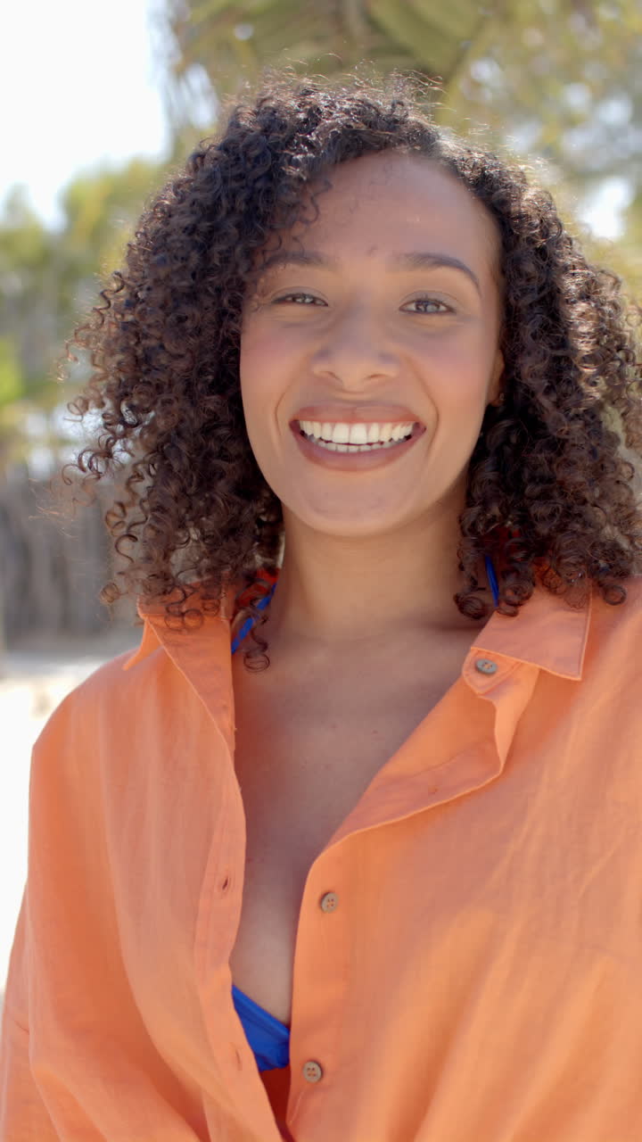 Vertical video of portrait of happy african american woman at beach house