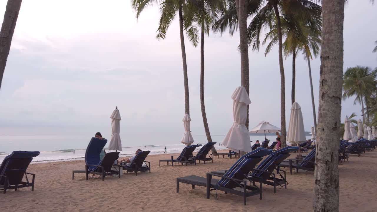 tumbonas de playa de lujo en cámara lenta con sombrilla en la playa de arena blanca