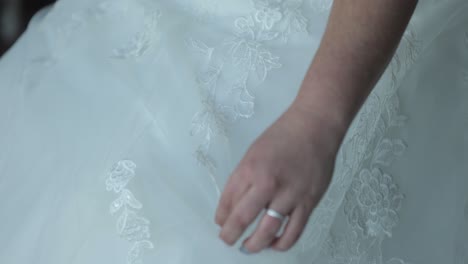 bride dressed up in a wedding gown for her wedding holding part of her dress in her hand while sitting on a chair