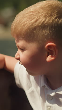 thoughtful little boy looks at river from sailing motorboat salon closeup. cute toddler child leans on bench back travelling by vessel on vacation