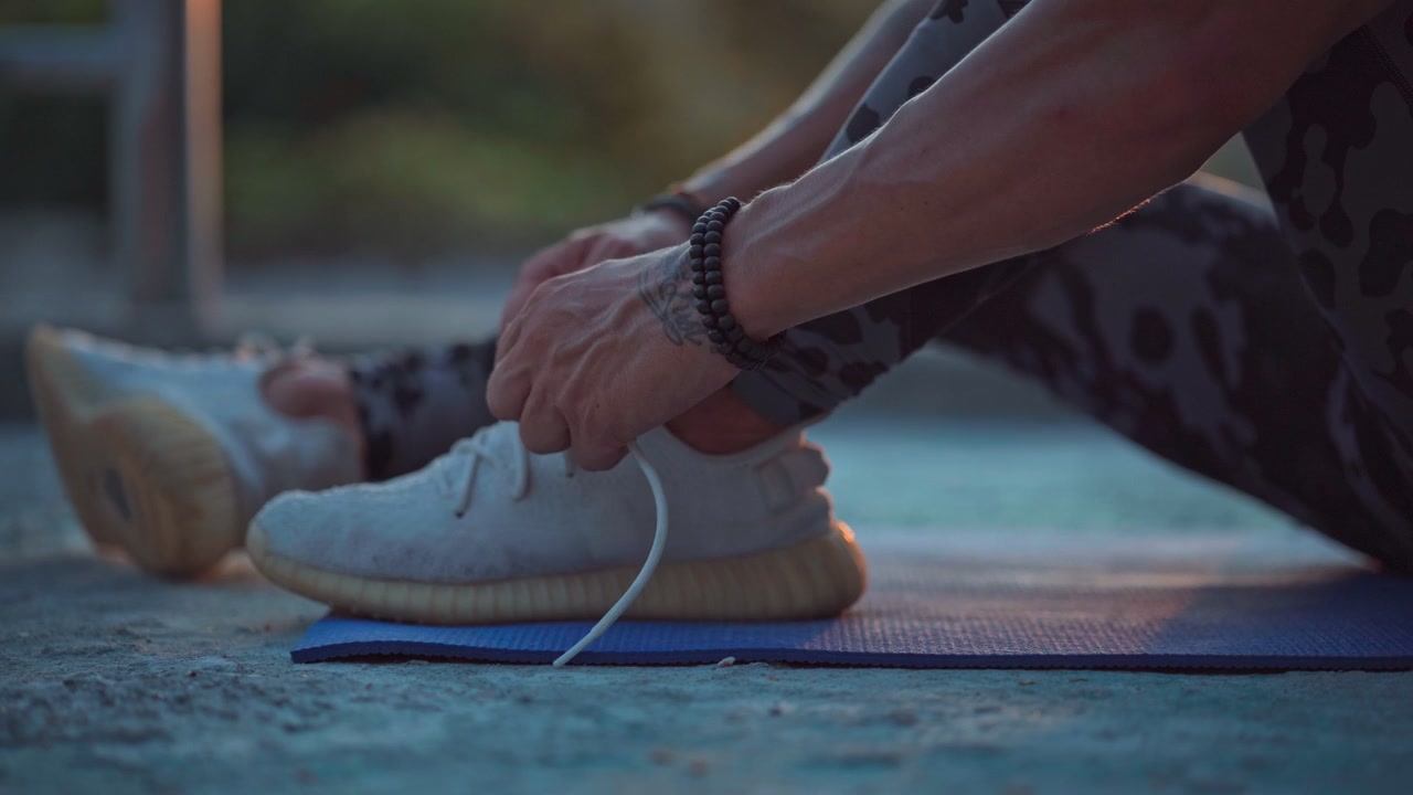 Persona che allaccia le scarpe su un tappetino da yoga all'aperto