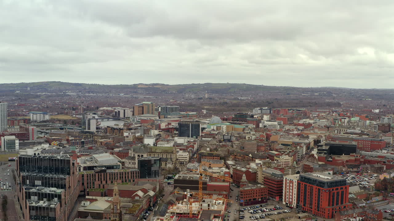 Expansive drone shot rising above Belfast's cityscape with distant hills forming natural backdrop