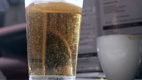 vaso de cerveza espumoso con burbujas que se elevan en el mostrador de la barra