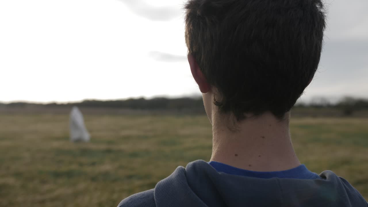 10대 소년이 예수를 쳐다본다 - 또는 흰 가운을 입은 남자 - 태양으로부터 빛나는 빛과 함께 멀리 서 있다