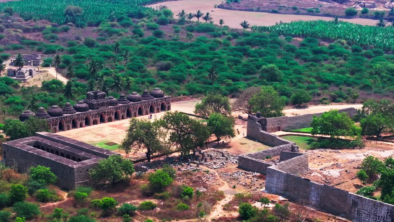 Stalle degli Elefanti con Casa delle Guardie, alberi e terreni agricoli ad Hampi, Karnataka, India. Di giorno, inquadratura in avvicinamento, inquadratura in elevazione, ripresa con drone, 4k.