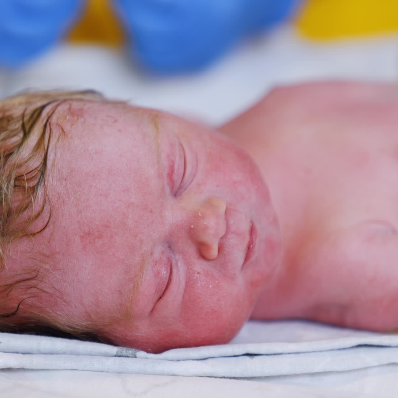 Winziges, süßes, kaukasisches Neugeborenes mit roten Haaren. Frischgebackenes Baby, das seine Augen leicht öffnet. Nahaufnahme