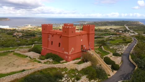 Drone-shot-orbiting-Mellieha's-Red-Tower,-also-know-as-St-Agatha's-Tower