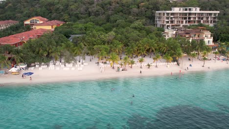 aerial view of the coast, green palms, umbrellas, resorts, on the sandy beach at sunset
