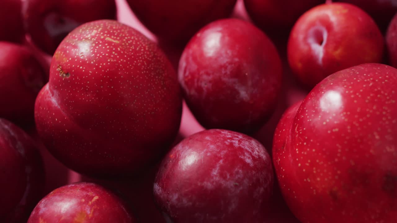 Video of fresh plums lying on pink surface
