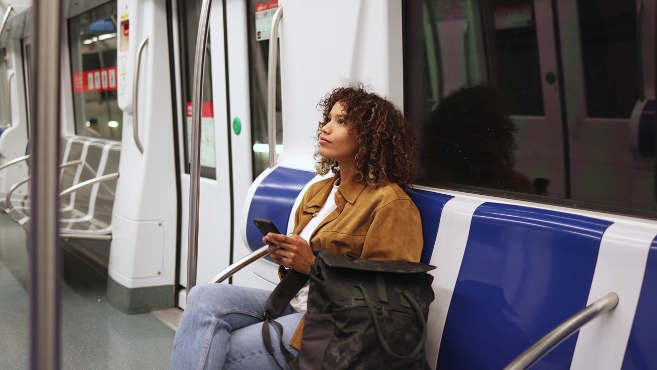 Young Woman Using Smartphone While Commuting on Subway Train