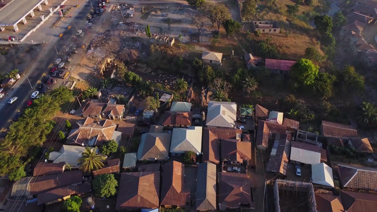 Pengambilan gambar jib ke atas yang indah dari rumah-rumah di pinggiran Abuja, Nigeria. Antrean panjang mobil yang melaju lambat terjebak kemacetan di jalan utama kota